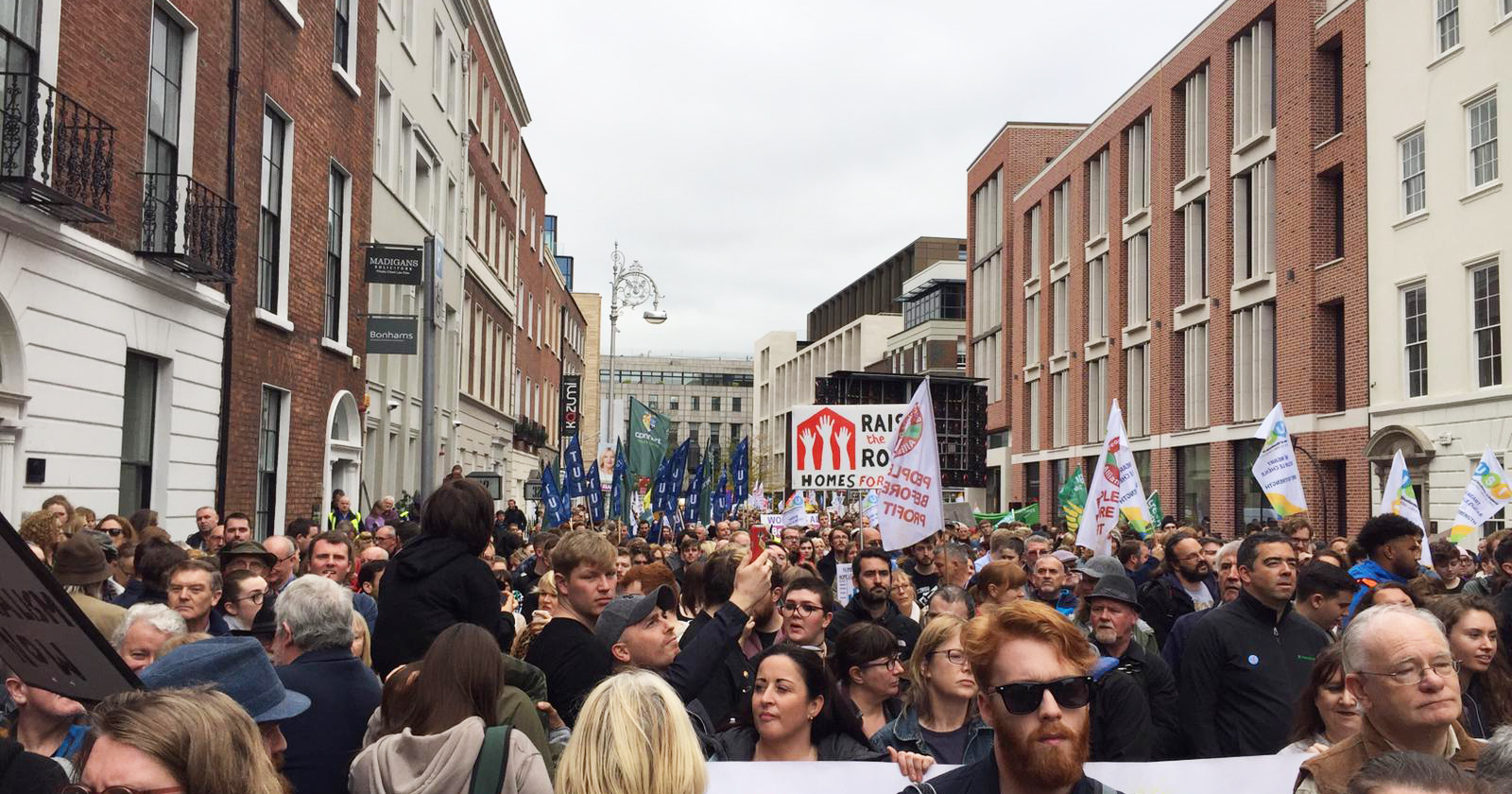 Hundreds of people fill the street outside Leinster House holding up banners in protest of the housing crisis
