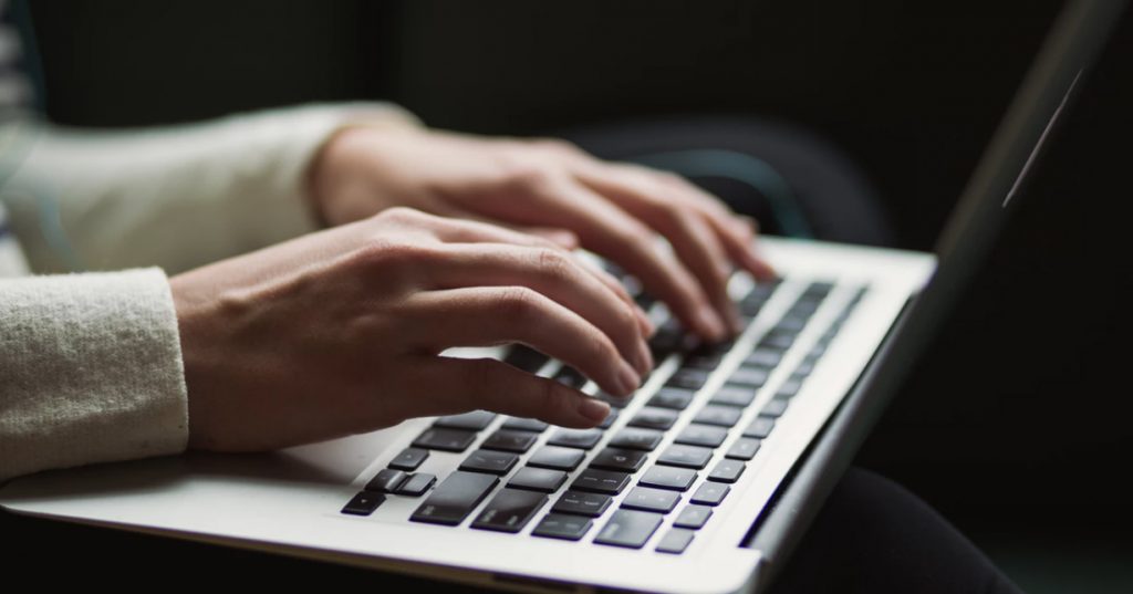 Image of two hands typing at a laptop. The google Talks At event will discuss hate speech online.