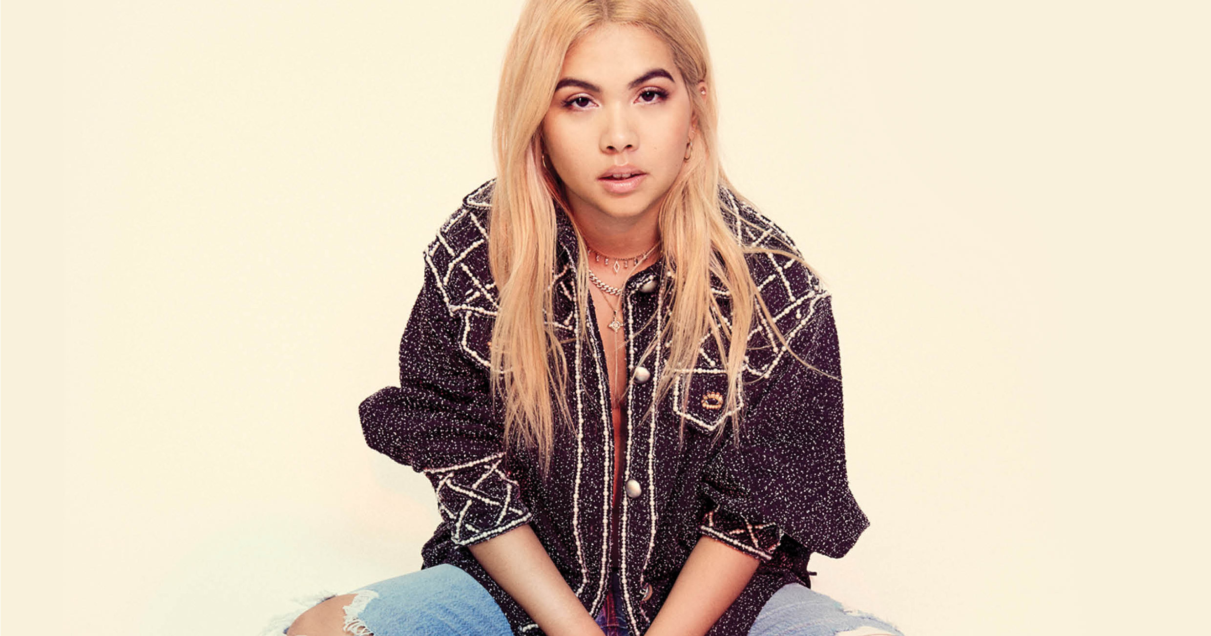 Hayley Kiyoko sitting down looking at the camera