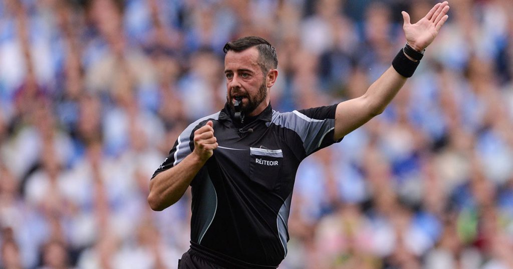 David Gough refereeing at a GAA match in Croke Park with hand up and blowing a whistle