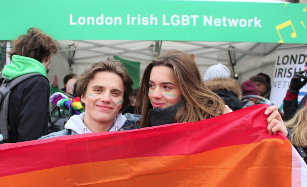 Two people holding a Pride flag ahead of the conference.