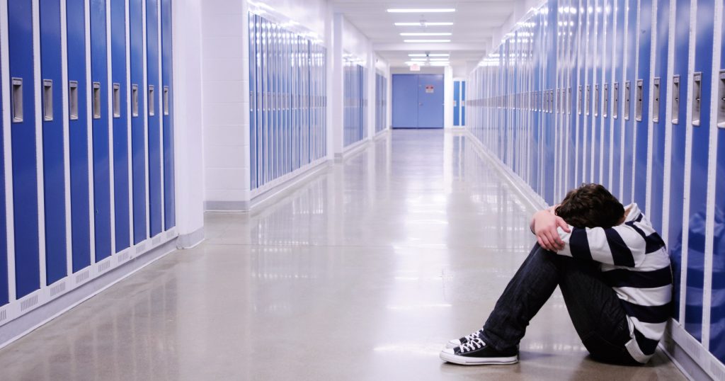 boy crying in a hallway in a school as a result of bullying