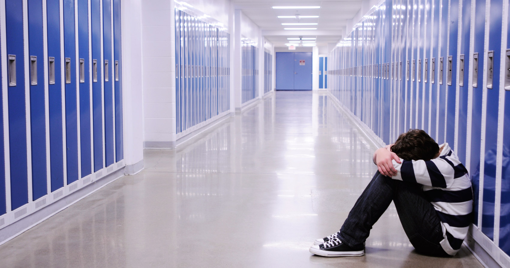 boy crying in a hallway in a school as a result of bullying