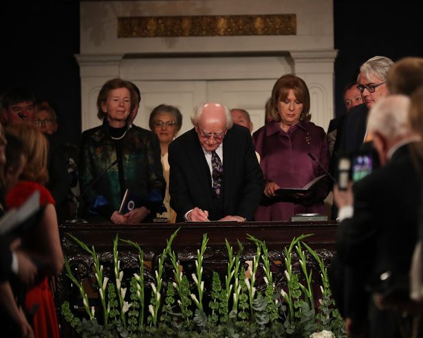 Michael D Writing in a book at his inauguration