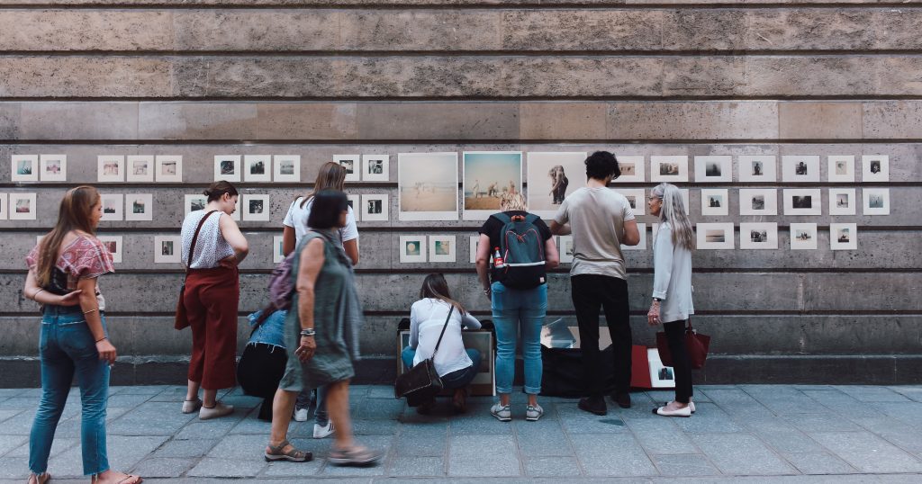 A photovoice exhibition with a group of people all staring at photos pinned to a wall