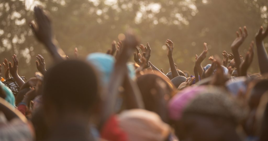 The hands of a crowd of Tanzanian people reaching for aid