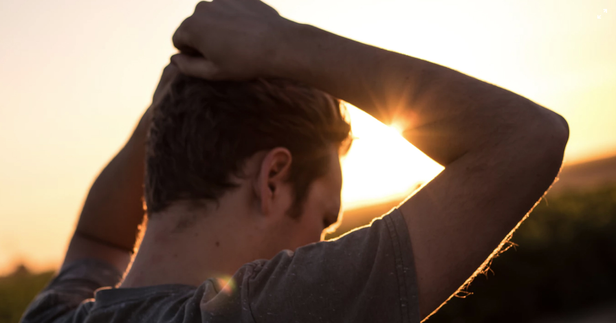 Man gripping his hair in the sunlight.