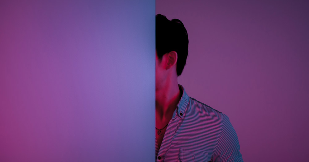 Person half hidden behind a purple wall.
