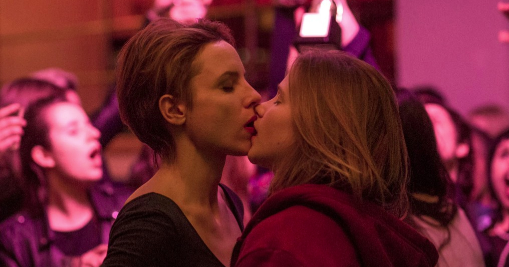 A still from the film 'Nina' - two women share a kiss in a busy bar.