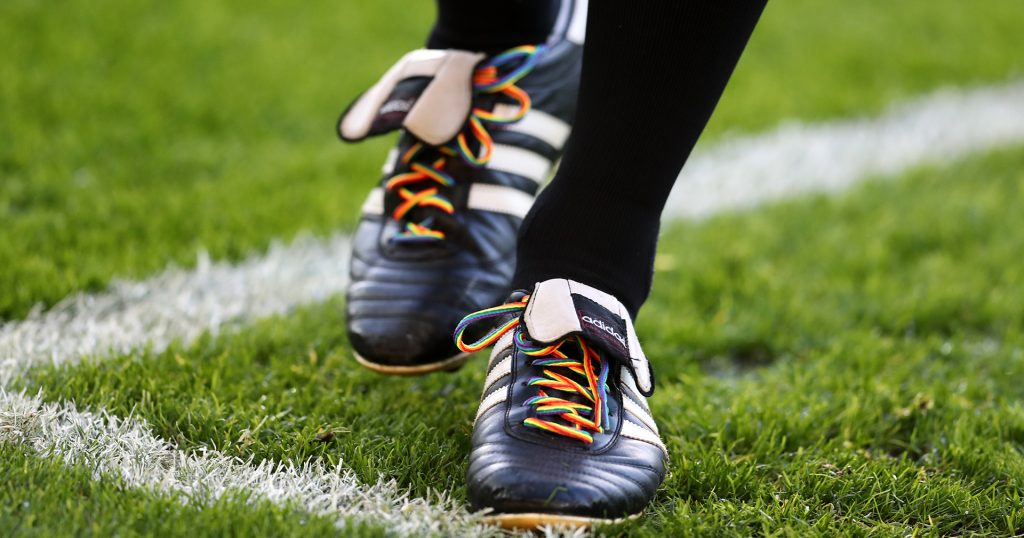 The feet of a Premier League footballer with rainbow laces in their boots