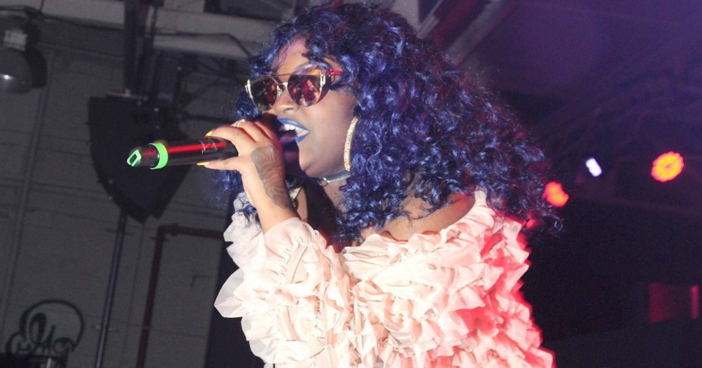CupcakKe performing on stage wearing a pink jacket and sun glasses