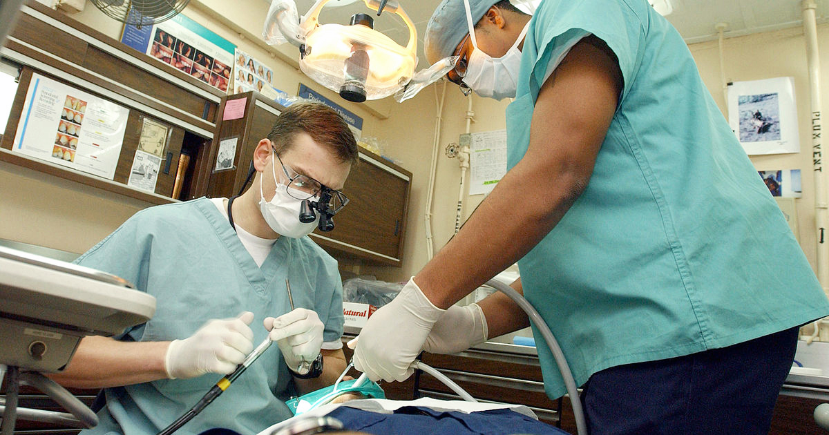 A dentist and his assistant carry out dental surgery