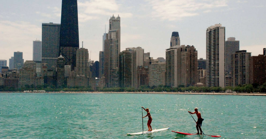 Two people paddleboard along the Chicago River.