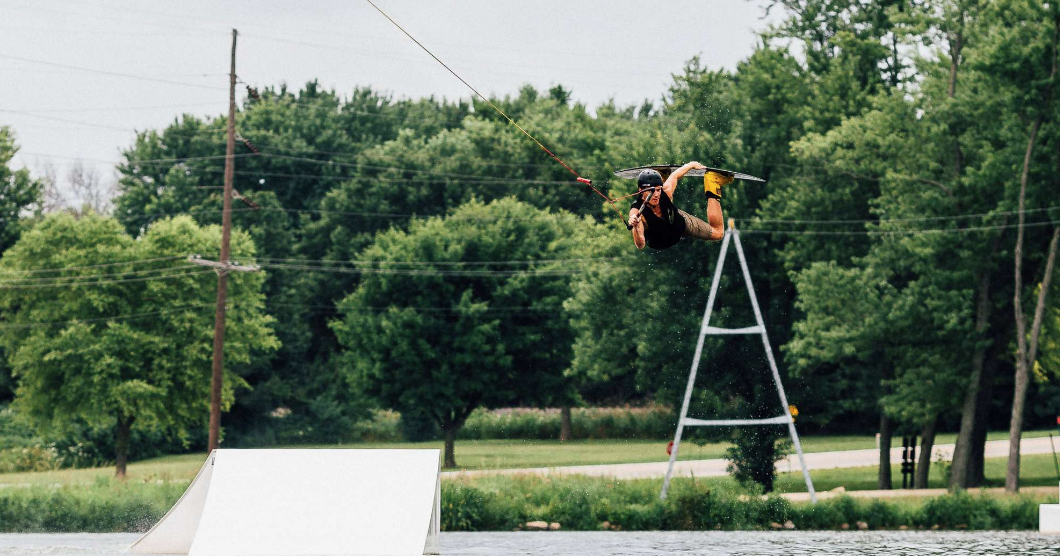 A man does wakeboarding over a lake