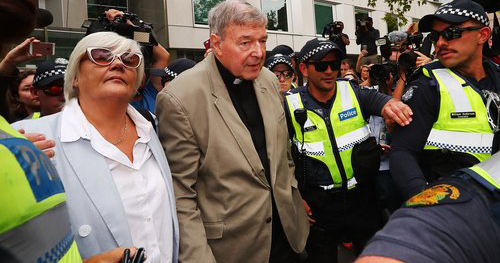 Cardinal George Pell is escorted by police.