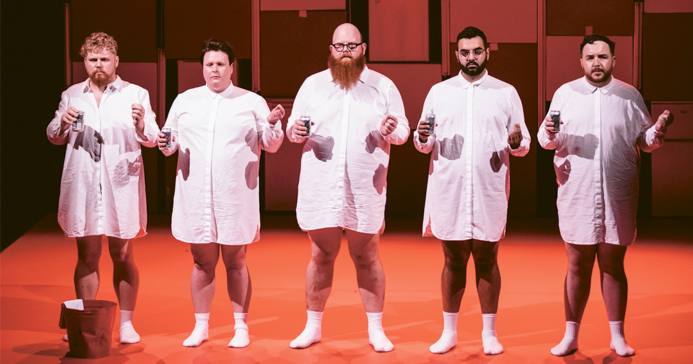 An image from the show Fat Blokes featuring five men in long white shirts standing on stage