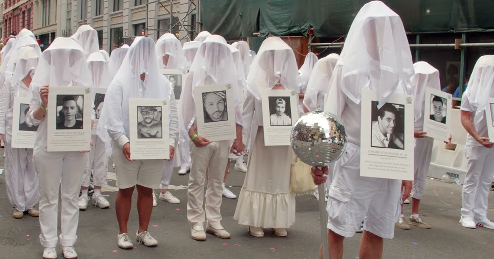 The Gays Against Guns group dressed in white wearing white veils casting the photos of people killed by guns