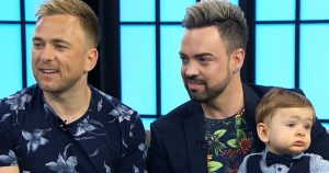 Jay, Aaron and their son sit together on a couch.