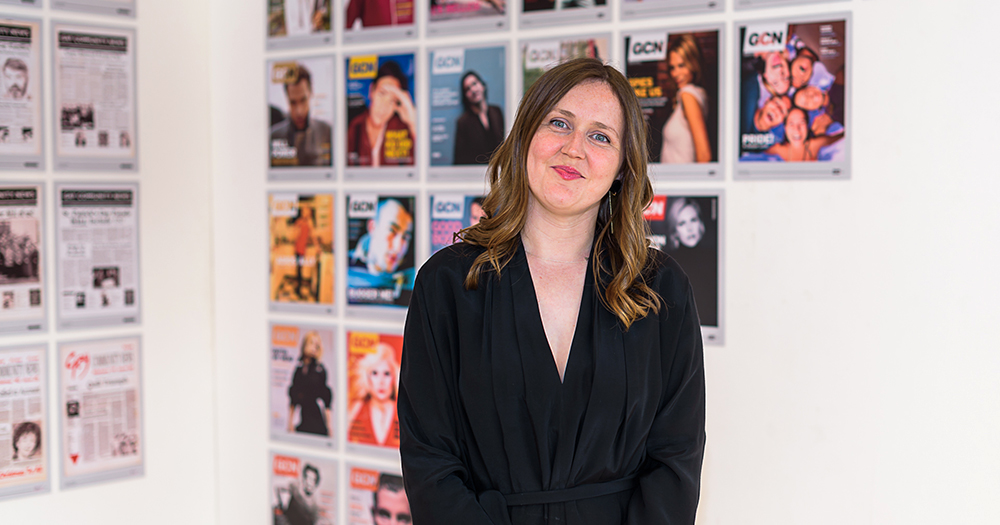 Managing Editor Lisa Connell at an exhibition in front of a wall of GCN covers