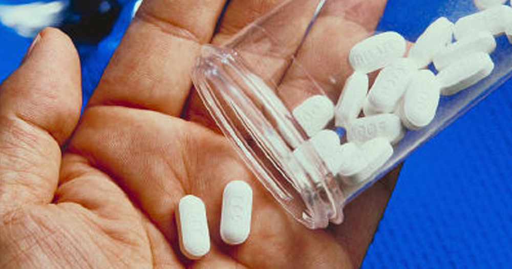 A person pours out two pills into their hand.