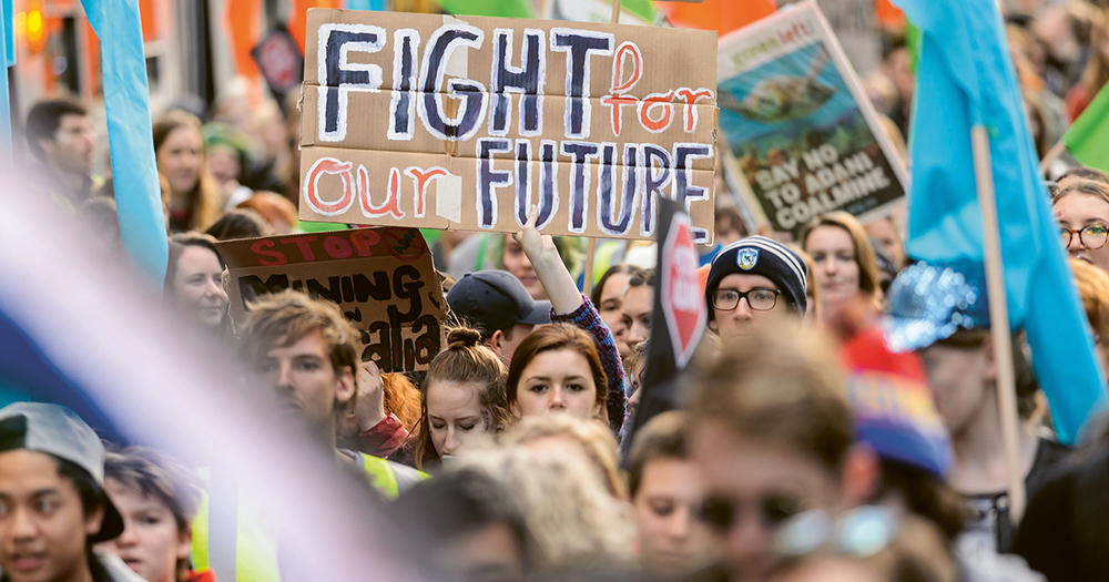 Crowds of young people protesting the climate crisis, holding up posters and banners