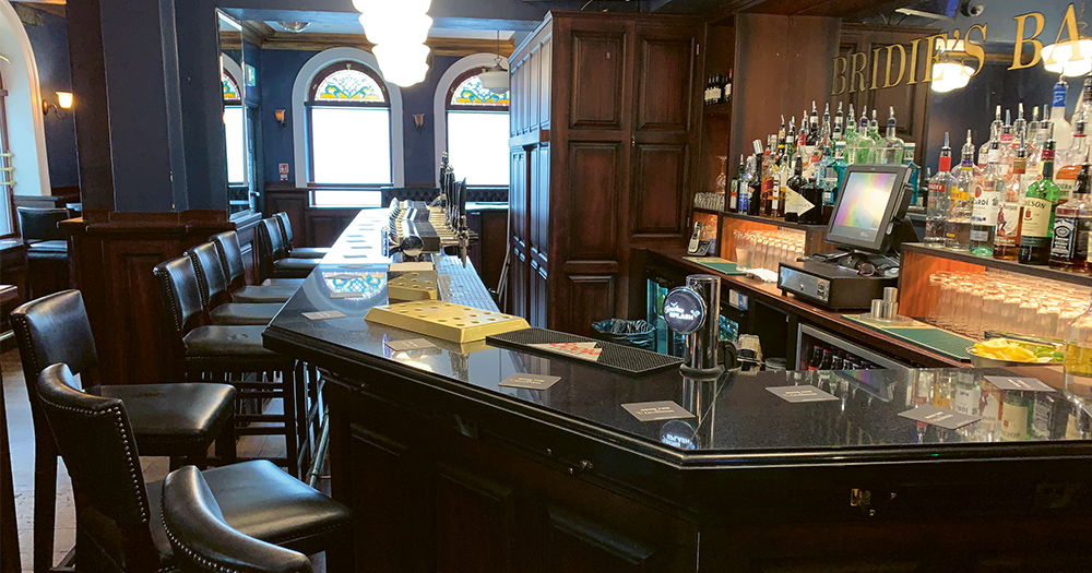 The interior of an empty bar, wood panel on the walls, rows of drinks at the back wall