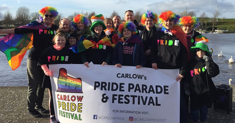 Group of rural organisers for Carlow Pride donned in rainbow clothing holding up sign which states: 'carlow pride parade & festival"