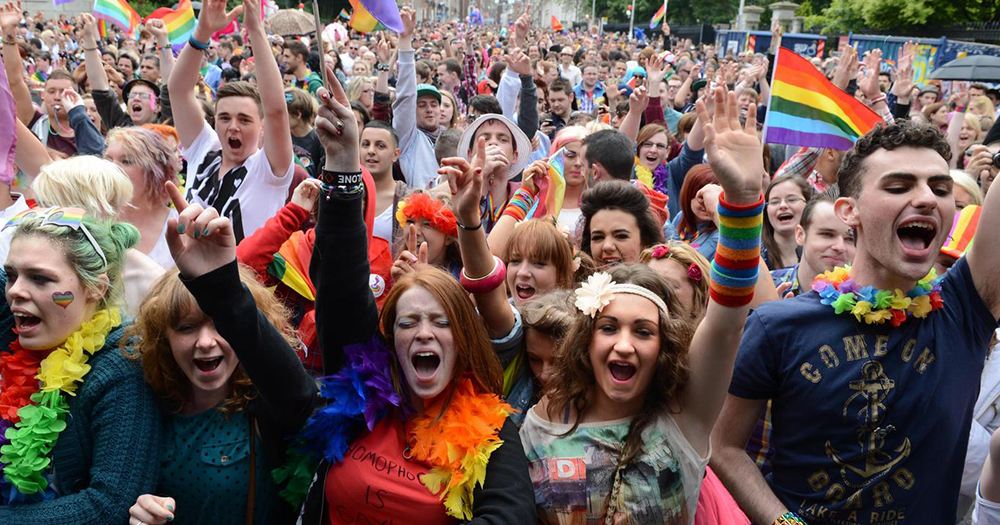 A huge crowd at Dublin Pride wearing rainbow coloured accessories and cheering
