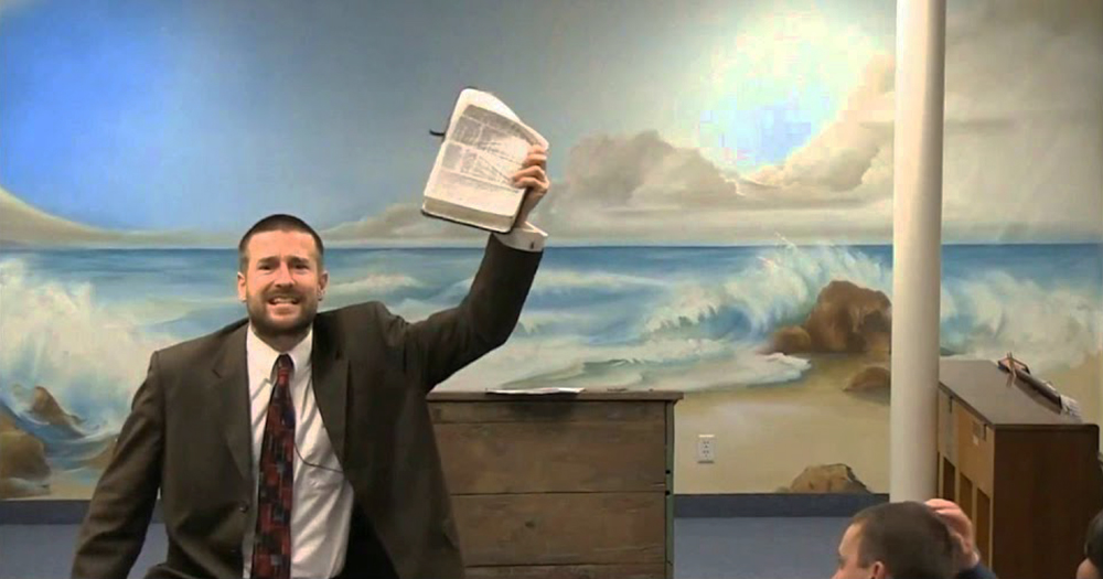 Pastor Steven Anderson delivering a rant to his congregation, a bible held above his head