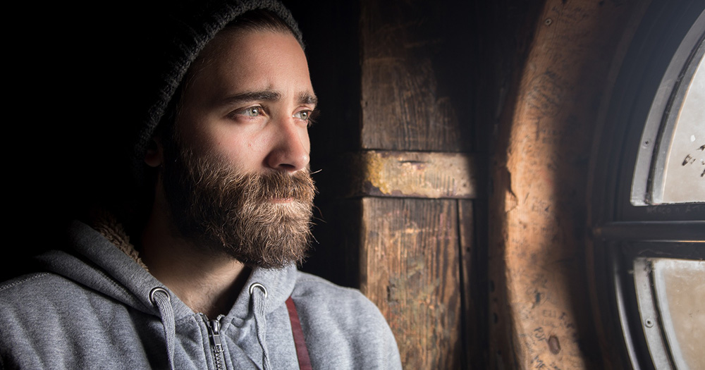 A man, unhappy like many gay fathers emerging from straight marriages, looks out a window