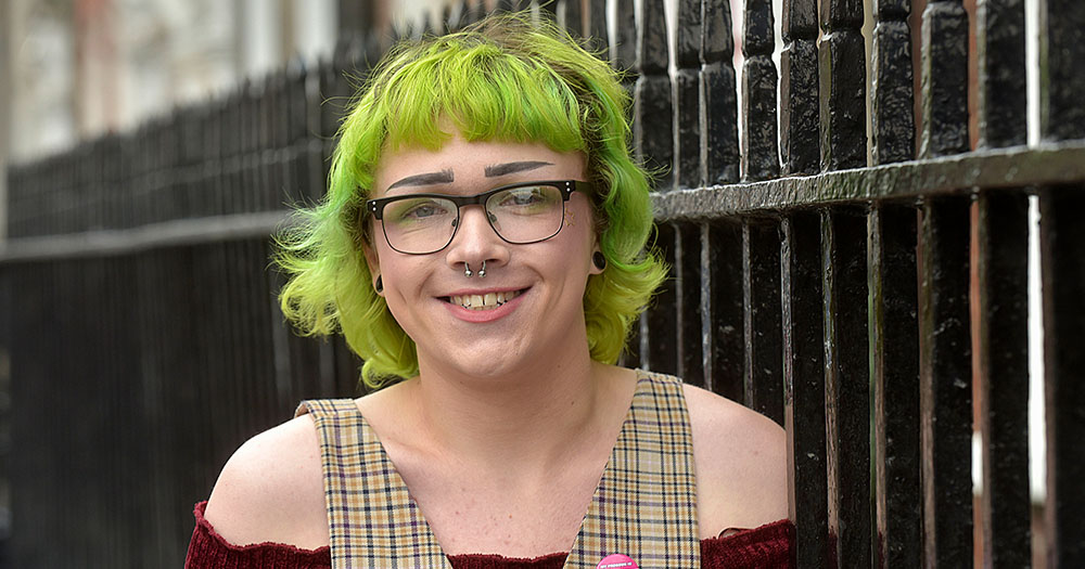 At the launch of the Youth Work Ireland resource, a smiling young trans woman stands by a metal railing