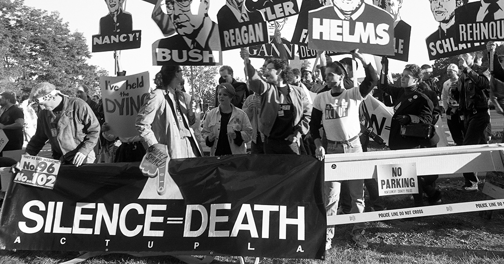 ACT UP hold signs with US government officials images during a HIV/AIDS protest in the 1980s