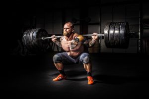 A heavily muscled man straining to lift a barbell