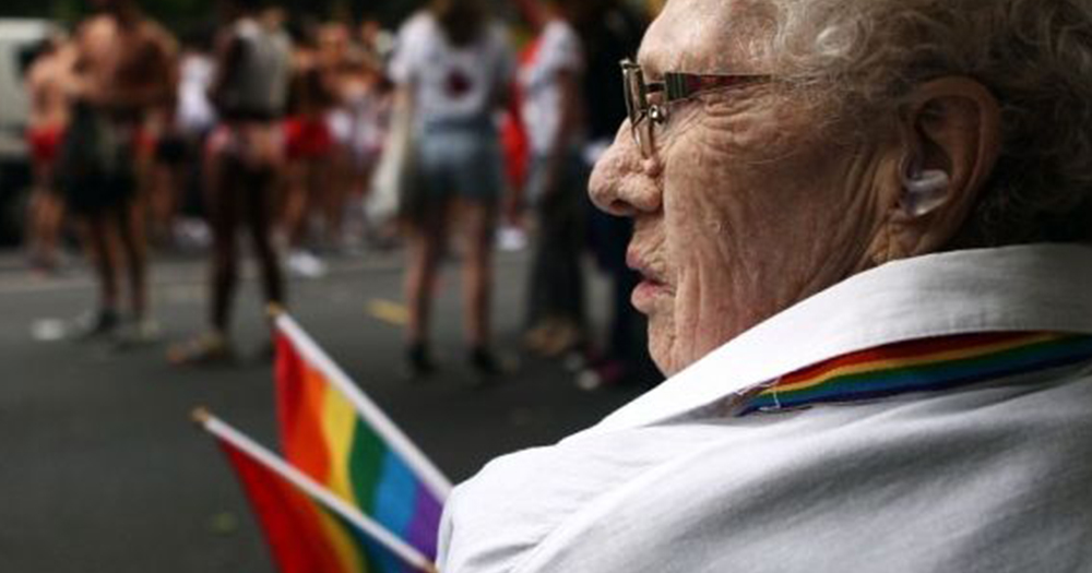 older woman holds pride flag