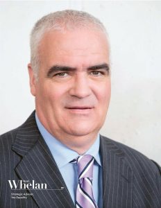 Noel Whelan in a suit against a white backdrop