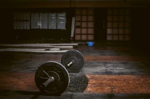 A dark gym hall, a huge barbell on the floor