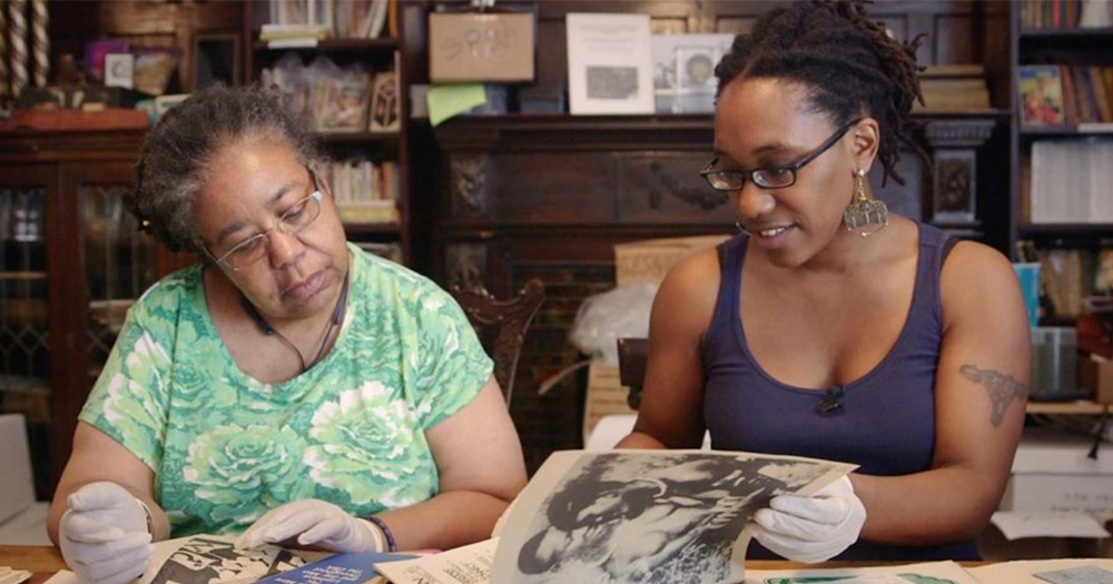 A still from The Archivettes featuring a younger and older woman looking through a photo album