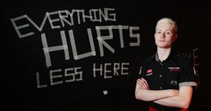 person from National Youth Theatre stands in front of sign reading "everything hurts less here"