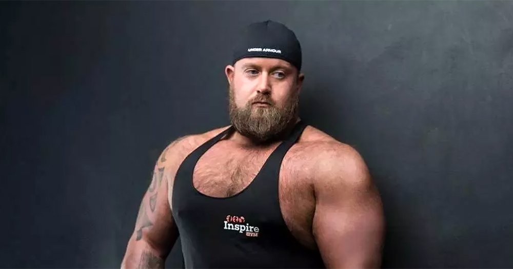 Ireland's first openly gay strongman Chris McNaghten wearing a tank top and a cap.