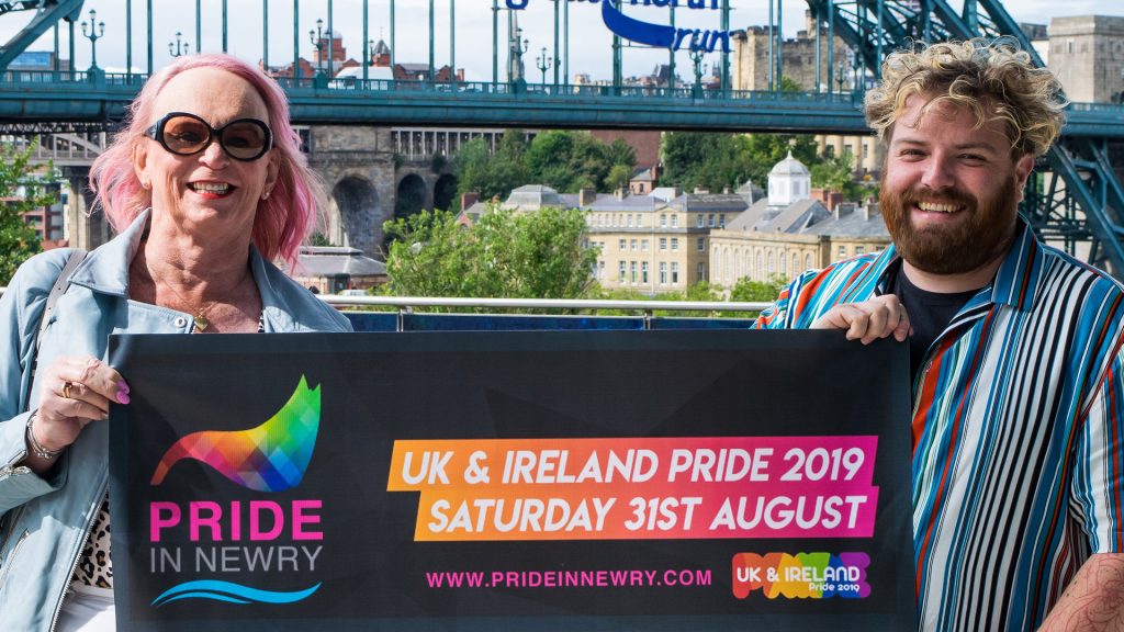 Newcastle Pride team members stand behind a banner which reads "Newry Pride"