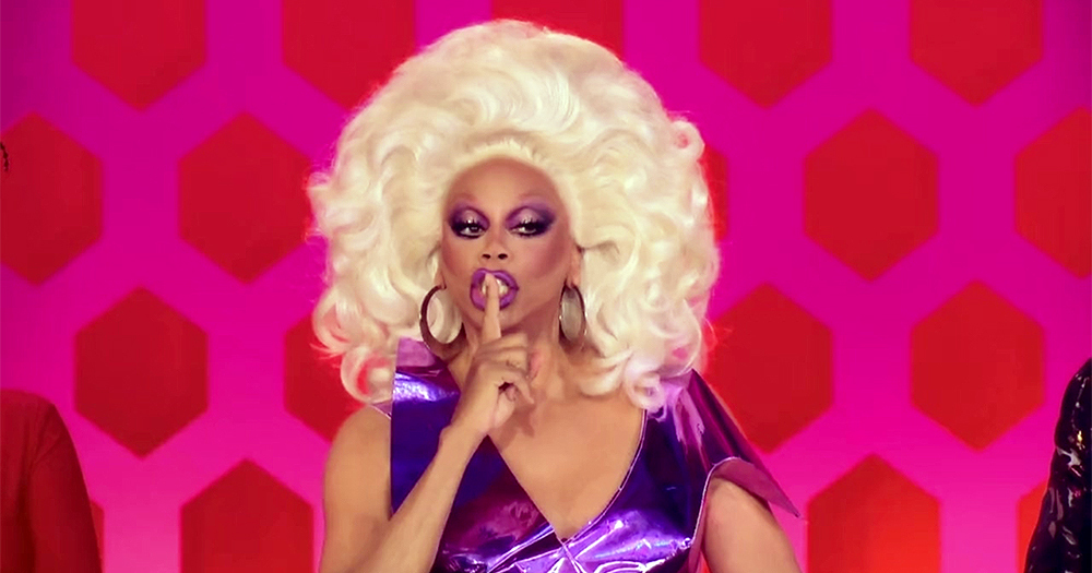 RuPaul, in full drag, makes a shushing gesture to the camera