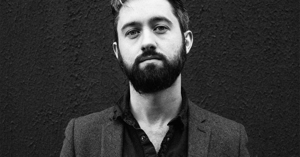Villagers frontman Conor O'Brien with a beard posing moodily against a wall