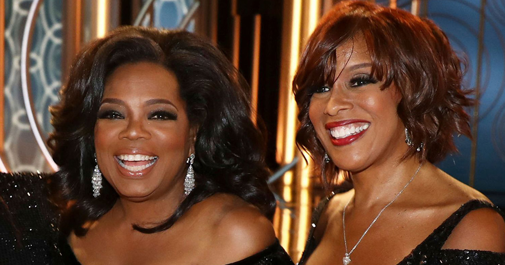 Oprah Winfrey and Gayle King both wearing black dresses and smiling at an event.