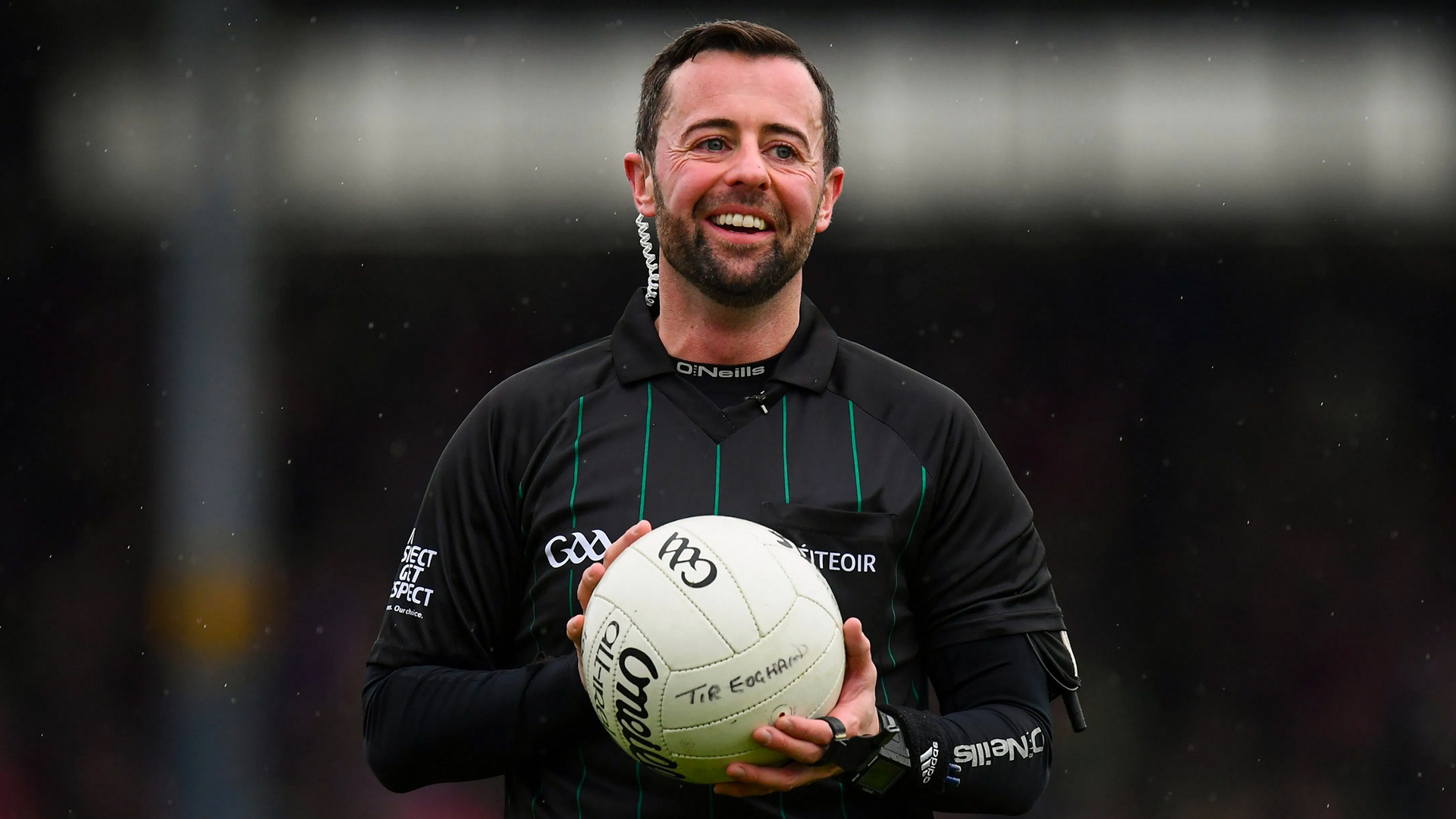 David Gough stands smiling in his referee uniform holding a GAA ball