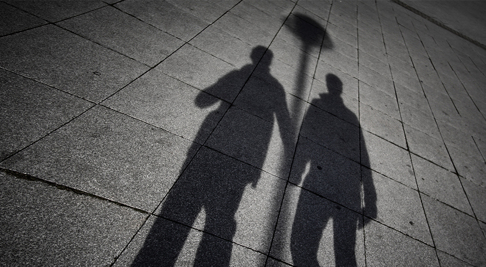prosecutions the shadows of two men holding hands