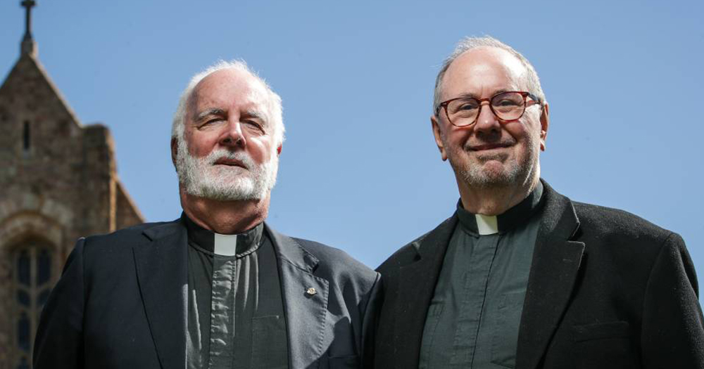 Married gay priests in their 50s standing outside a church