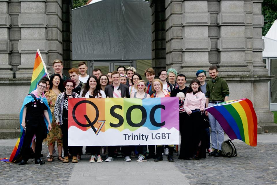 Members of Trinity's QSoc stand with QSoc sign