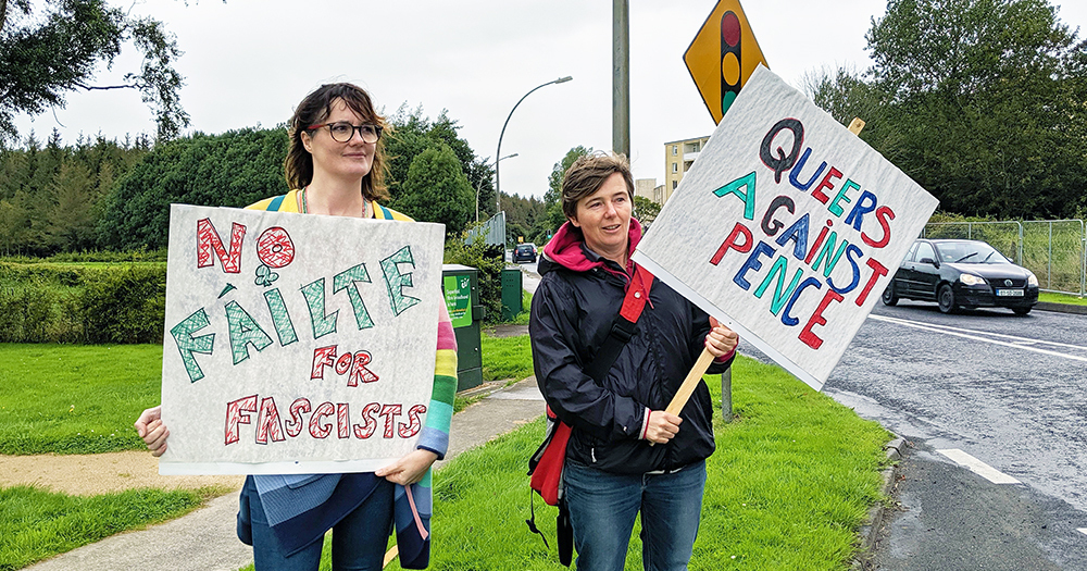 Queer Irish poet, Sarah Clancy, is joined by another protestor as they hold signs reading “No fáilte for fascists” and “Queers against Pence” outside of Shannon Airport.
