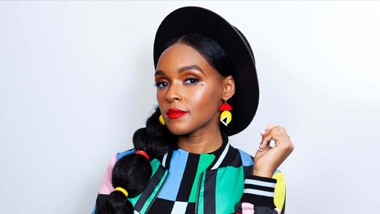 Singer Janelle Monáe wearing a black hat and a colourful top