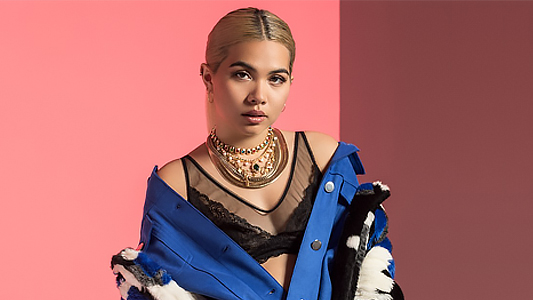 One of the singers of colour that should be on your playlist: Hayley Kiyoko wearing a blue unbuttoned top.